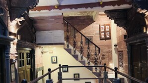 Eine Treppe mit aufwendiger Balustrade und Steinmauern, die zu einer Tür mit Glasfenster führt.