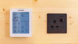 Een Samsung slimme thermostaat en een stopcontact op een houten oppervlak.