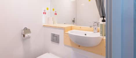 A modern bathroom with a white toilet, a wooden vanity with a sink, and a mirror.