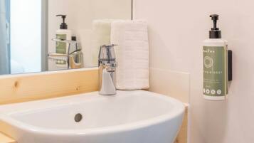 A bathroom with a white sink, a mirror, a towel, and a bottle of hair and body care product.