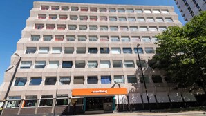 Een hotel met meerdere verdiepingen, een gelijkmatige gevel, een opvallend oranje bord met EasyHotel erop en een heldere lucht erboven.