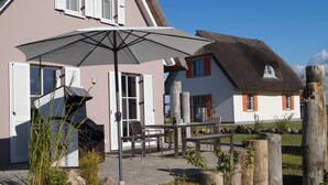 A house with a thatched roof, white shutters, and a patio with outdoor furniture.