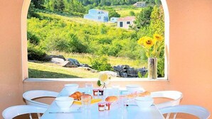 A table with a view of a green landscape with houses and a vase of sunflowers. - Village vacances Léo Lagrange Montbrun (Montbrun-les-Bains)