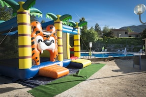 Ein aufblasbarer Spielbereich mit Tiger-Design, umgeben von Palmen und einem Pool.
