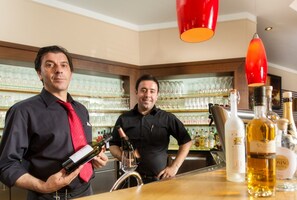 Två personer sitter vid en bar med vinflaskor och vinglas.