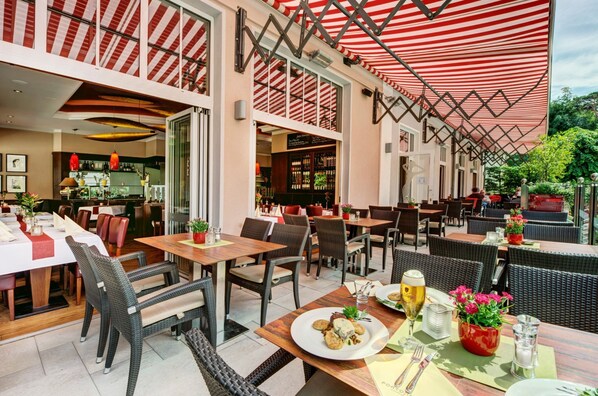 An outdoor dining area with wicker furniture and a red-striped awning.