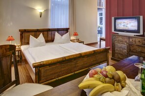 A hotel room with a bed, bedside tables, a television, and a fruit basket.