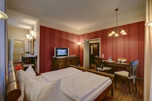 Ein Hotelzimmer mit Bett, Schreibtisch, Stuhl, Fernseher und Spiegel.