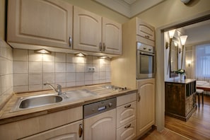 A modern kitchen with light wood cabinetry, a stainless steel sink, and built-in appliances.