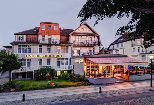 A hotel with a restaurant on the ground floor, a balcony, and a sign that reads 'NORDISCHER HOF'.