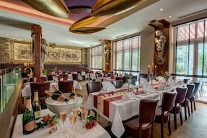 A restaurant with multiple tables set for dining, a bar area with bottles, and a large decorative sculpture on the wall. - Double room with kitchenette - Strandhotel Nordischer Hof (Kühlungsborn)