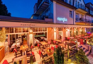 A restaurant with outdoor seating, a sign reading 'PORTOFINO,' and a balcony area.