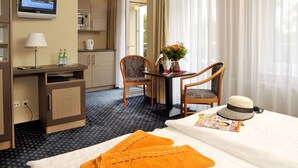 Een hotelkamer met een bed, een bureau met een computer, een stoel, een televisie en een raam met gordijnen.