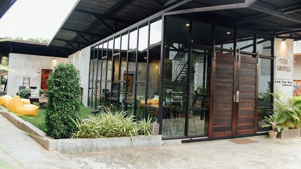 A modern building with large glass windows, a covered entrance, and outdoor seating. - The Simple Koh Yao Noi (Ko Yao)