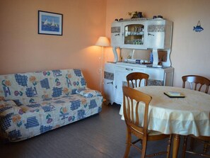 Relax in this inviting living space with a dining area, featuring a sofa, cabinet, and dining table.