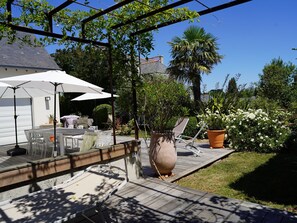 Un espace patio aménagé avec du mobilier d’extérieur, une pergola et des plantes en pot.