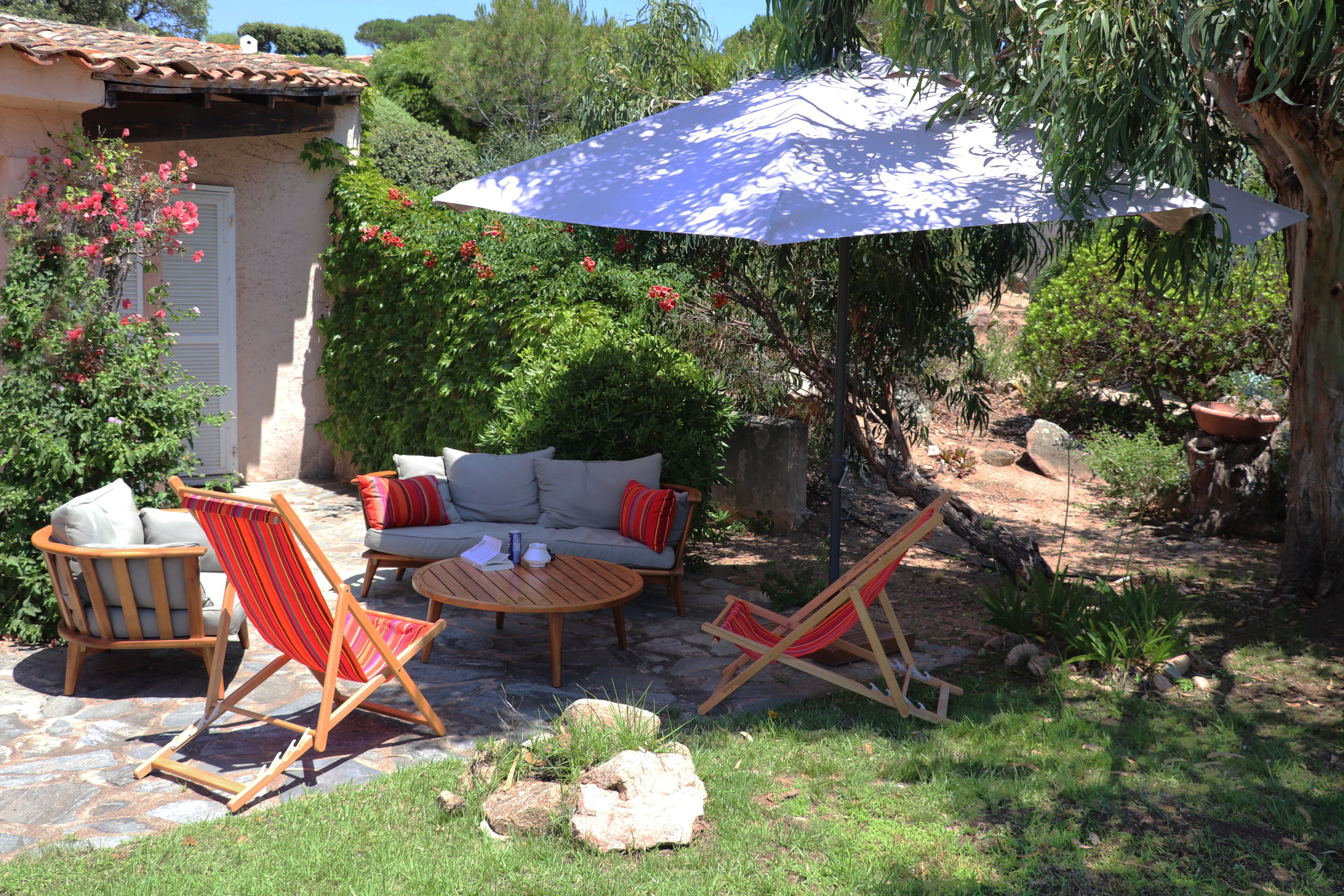A patio with outdoor furniture, including a sofa, chairs, and a table, under a large umbrella.
