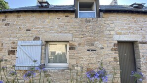 Un bâtiment en pierre doté d’une petite fenêtre, d’une porte et d’un puits de lumière.