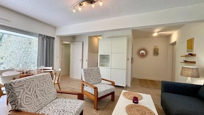 Un salon moderne comprenant un canapé, un fauteuil et un coin repas avec une table et des chaises.