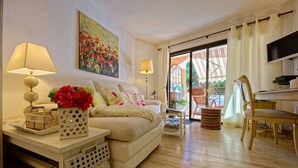 Ein Wohnzimmer mit Sofa, Lampe, Gemälde und Blick durch eine Glastür.