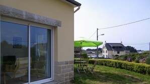 A house with a sliding glass door, a green umbrella, and outdoor furniture. - T2 with open view on the port of Ploumanac'h, Perros-Guirec (Perros-Guirec)