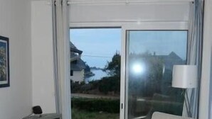 A living room with a television, a sofa, a coffee table, and a view of the outdoors. - T2 with open view on the port of Ploumanac'h, Perros-Guirec (Perros-Guirec)