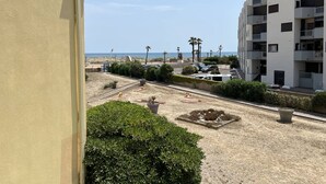A residential area with a sandy beach, a parking lot, and a multi-story building with balconies. - T2 + Mezzanine, 6 pers, Terrace, BBQ, Close to the beach (Port Barcarès)