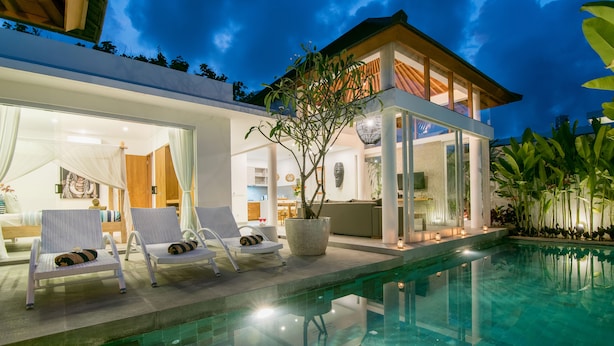 Um resort moderno com piscina, espreguiçadeiras e interior bem iluminado.