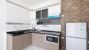 A kitchen with a black countertop, a built-in oven, a microwave, and a refrigerator. - Sanga Villas (Rawai)