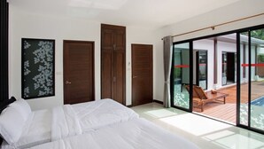 A bedroom with a large bed, sliding doors leading to a balcony with a pool and lounge chairs. - Sanga Villas (Rawai)