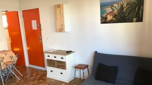 Une pièce avec un canapé gris, un meuble en bois, une petite table et une chaise.