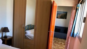 Une chambre à coucher avec un lit, une armoire, une table de chevet et une fenêtre avec des rideaux.