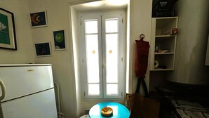 Une cuisine compacte comprenant un réfrigérateur, une petite table avec un saladier, et une porte dotée de deux fenêtres.