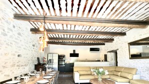 A dining area with a long wooden table set for a meal, a sofa, and a small round table with a vase. -  Mas Le Félibre **** (Caumont-sur-Durance)