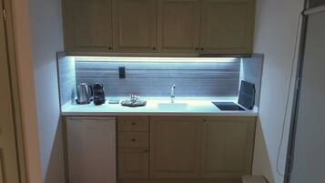 Una cocina compacta con un lavabo, una cafetera y un refrigerador pequeño.