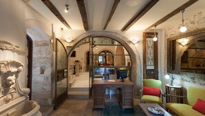 Un interior rústico con paredes de piedra, vigas de madera y un comedor con mesa y sillas.