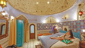 Una habitación con una cama grande, una puerta azul y un techo con diseño.