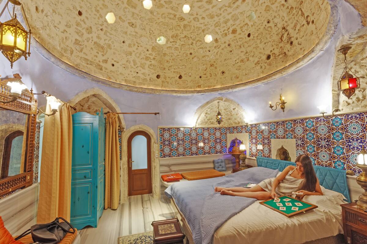 Una habitación con una cama grande, una puerta azul y un techo con diseño.