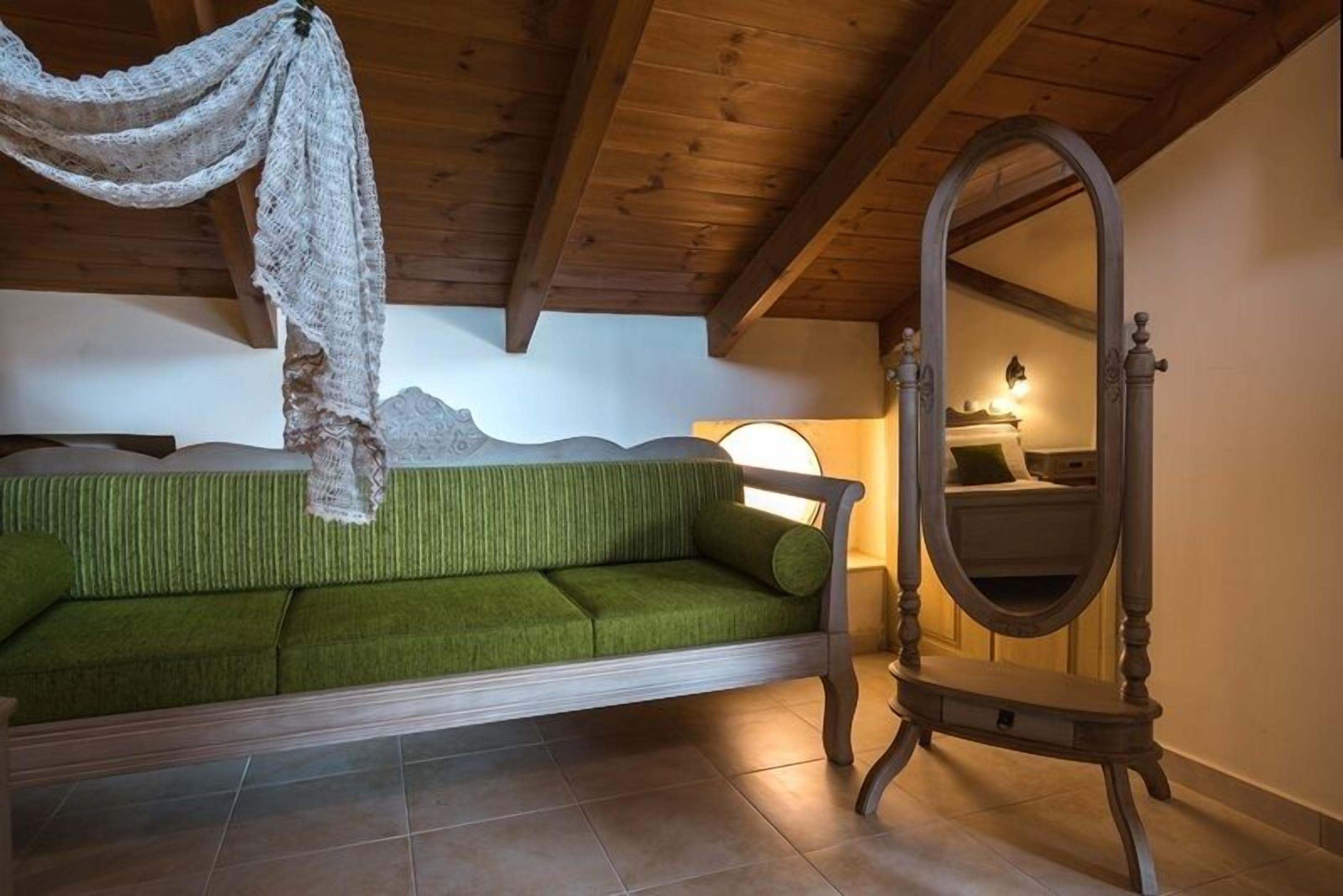 A cozy room with a green sofa, a wooden ceiling, and a large mirror.