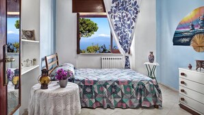 A bedroom with a bed, a window with a view, a bedside table with a lamp, and a dresser. - Peter's House (Sorrento)