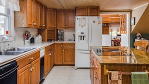 A kitchen with wooden cabinets, a refrigerator, a dishwasher, and a countertop with a sink. - Mountain Majesty ~ Country elegance at its best! (Huntsville)