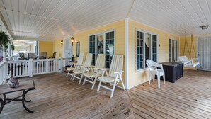 A covered porch with wooden flooring, white chairs, a table, and a swing chair. - Mountain Majesty ~ Country elegance at its best! (Huntsville)