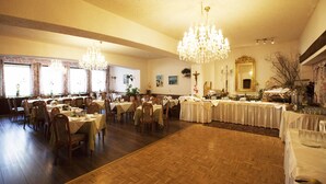 A spacious dining hall with multiple tables, chandeliers, and a large mirror. - Partenerhof (Gaschurn)