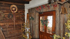 A rustic wooden interior with a wooden door, decorative wreaths, and a Christmas tree. - Partenerhof (Gaschurn)