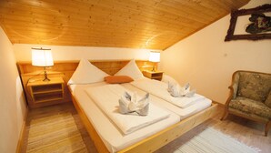 A wooden ceiling, a bed with two pillows, a chair, and a nightstand with a lamp. - Partenerhof (Gaschurn)