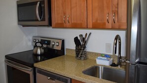 A kitchen with wooden cabinets, stainless steel appliances, and a granite countertop. - Bright and Spacious Corner Studio Unit with Wrap Around Lanai (Kihei)