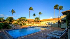 A swimming pool with lounge chairs and palm trees. - Bright and Spacious Corner Studio Unit with Wrap Around Lanai (Kihei)