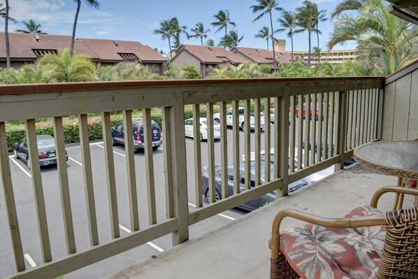 A balcony with a view of a parking lot and palm trees.