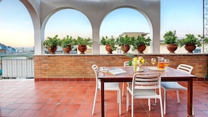 A terrace with a table set for dining, surrounded by potted plants and a clear view of the cityscape. - Skyline Sorrento (Sorrento)