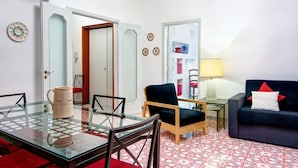 A living room with a glass table, a dark blue sofa, a wooden chair, and a red rug. - Skyline Sorrento (Sorrento)